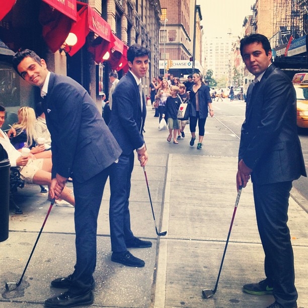 Trio of gentleman outside of balthazar posting with golf clubs in soho